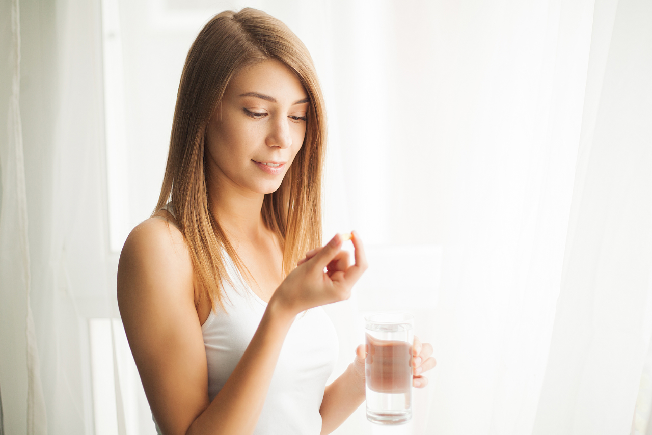 young teen female holding a pill in her hand wanting to know can teens take ashwagandha?