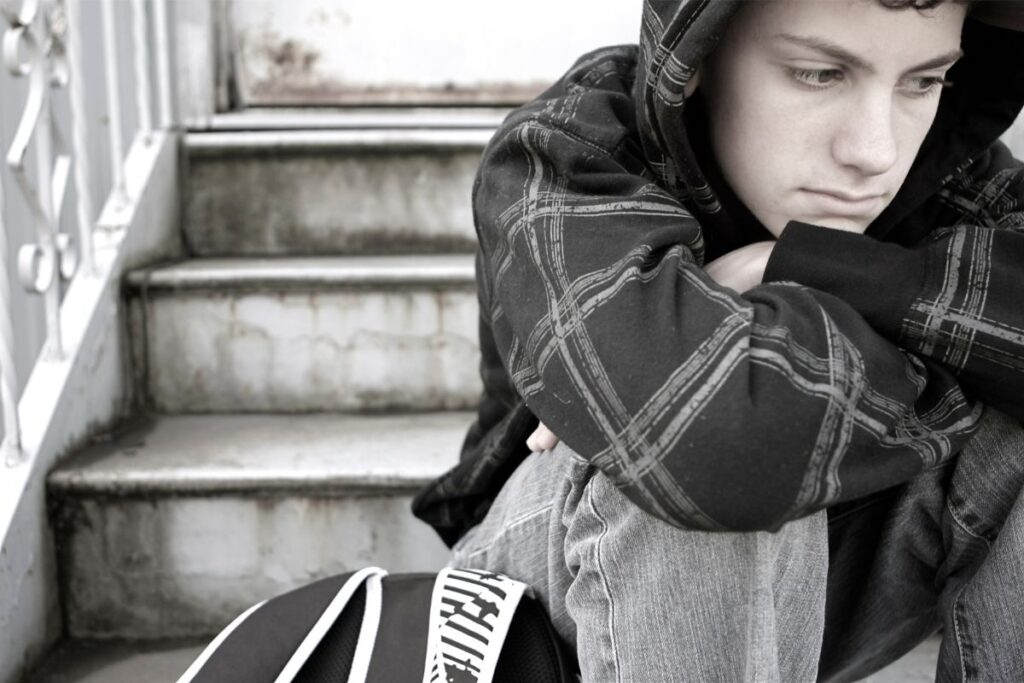 teen boy sits alone